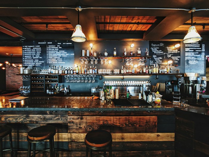 A neighborhood pub with a wooden bar and warm pendant lights